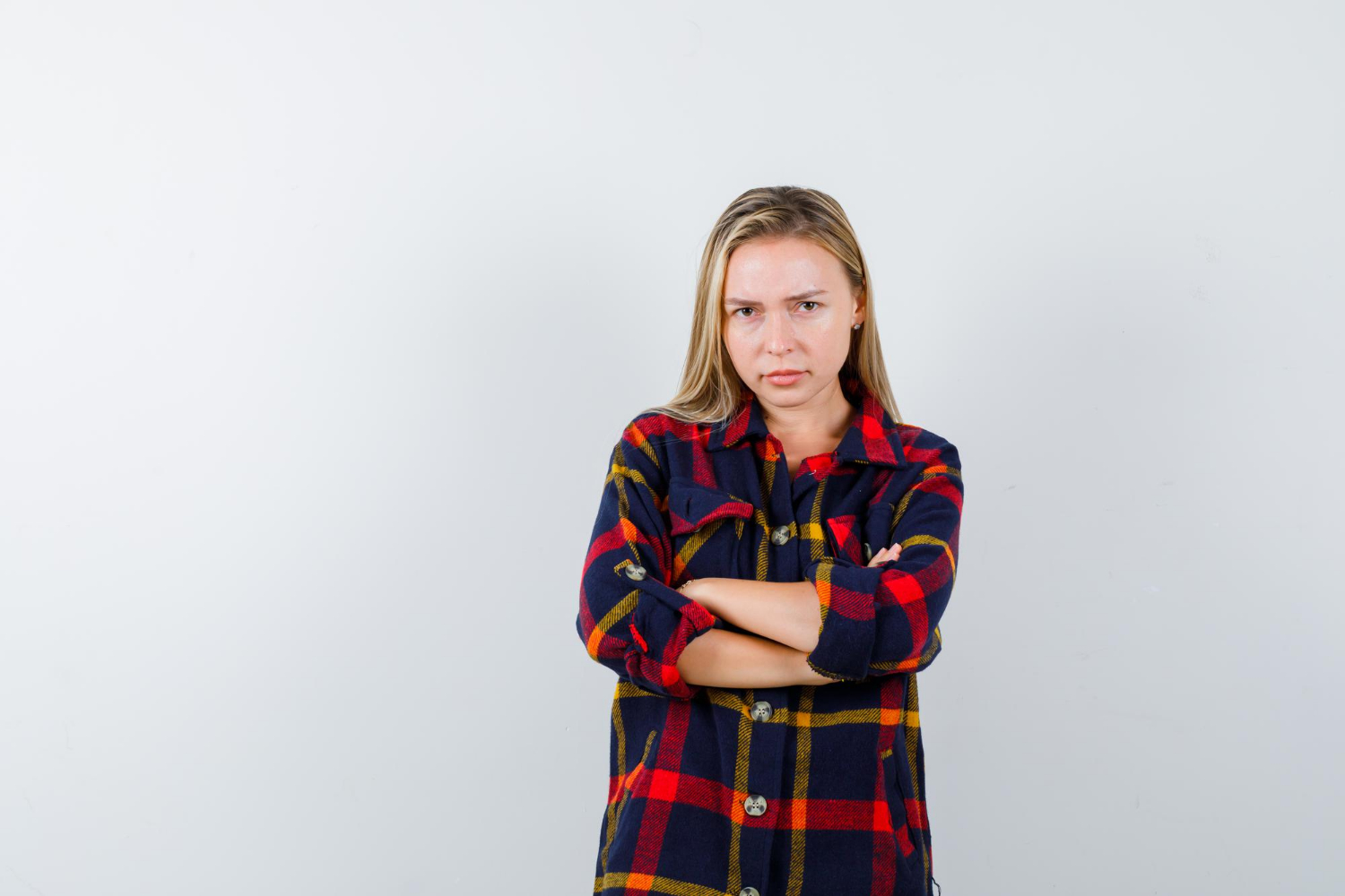 Egy fiatal nő dühösen összekulcsolt karokkal | Forrás: Freepik